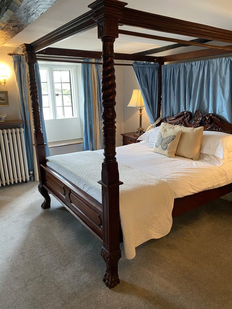 Double bedroom with four-poster bed and soft furnishings at Guyers House Hotel
