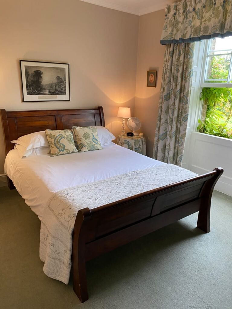 Double bedroom with view into garden and soft furnishings at Guyers House Hotel